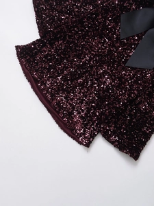 Detailed macro view of dark burgundy sequins and a black satin bow on the dress