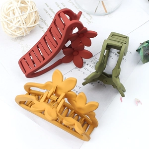 Matte flower hair claws in red, amber, and green shown on a clean white desk