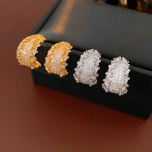 Détail de boucles d'oreilles en forme de C plaquées or et argent avec zircons brillants