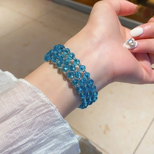 Detail of a three-layer beaded bracelet featuring blue faceted crystals and silver spacers