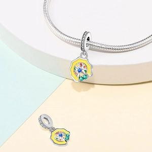 Detailed view of silver charm with yellow enamel and colorful stones on snake chain