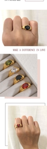 Detail of oval gemstone rings with ribbed gold bands in red, black, and green