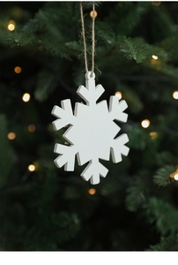 Close-up of white wooden snowflake ornament hanging on a green Christmas tree