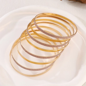 Detailed macro view of 8-piece gold-tone bracelets featuring polished and frosted finishes