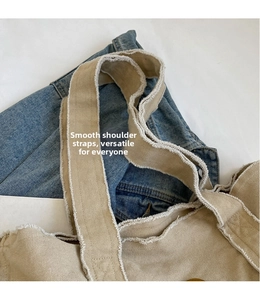 Detailed macro of beige canvas tote bag showing wide straps and vintage raw edge texture