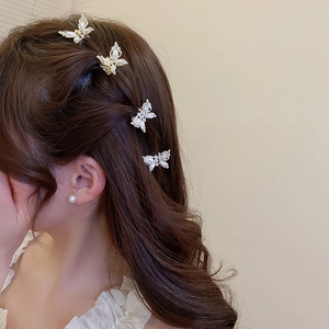 Detailed view of elegant gold butterfly hair clips with pearls on a model braid