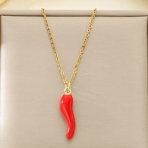 Gros plan d'un collier doré avec pendentif piment rouge émaillé dans un coffret