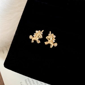 Close-up of gold-plated unicorn stud earrings with clear zircons on black velvet