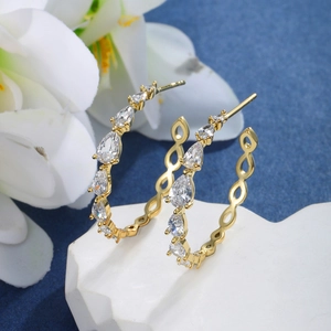 Close-up of gold hoop earrings with pear-cut cubic zirconia on a dark blue background