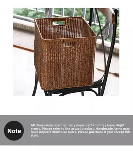 Detail of hand-woven dark brown storage basket with cutout handles on a rustic chair