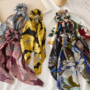 Detail of four floral satin scrunchies with long ribbons in blue, pink, and yellow