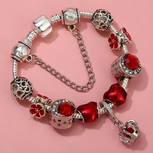 Close-up of silver charm bracelet with red floral pendants, heart beads and crown charm