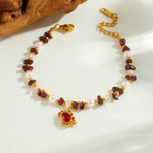 Bracelet doré avec pendentif crabe, perles de pierre colorées et nacre sur fond beige