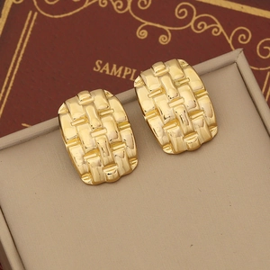 Golden irregular geometric earrings with woven metal texture on leather display