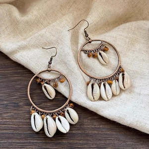 Detail of bohemian hoop earrings with natural conch shells and brown wooden beads