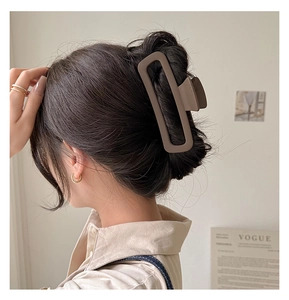 Detail of a large matte brown rectangular shark hair clip on a woman's hair
