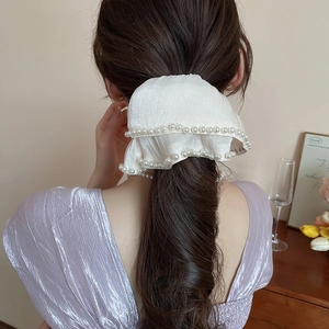 Close-up of a white pleated hair scrunchie with elegant pearls on brown ponytail