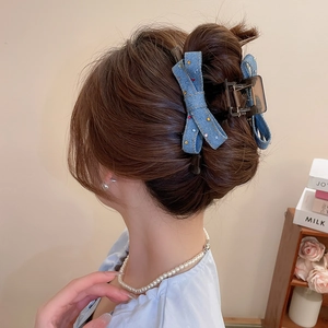 Detail of blue denim bow hair claw with colorful rhinestones on a back hair bun styling