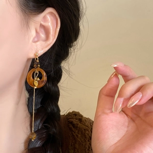 Macro view of long asymmetric resin earrings with tiger eye flower drop on model