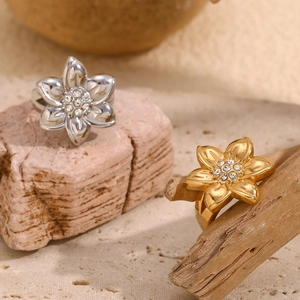 Macro shot of gold and silver flower rings with cubic zirconia on a natural rock texture