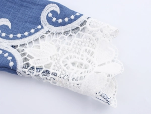 Detailed view of elegant blue denim cuffs with intricate white lace patchwork and embroidery