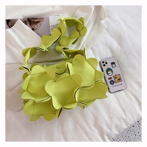 Detail of neon green petal-shaped pleated handbag on a stylish lifestyle background