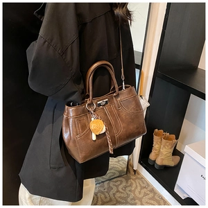 Détail d'un sac à main vintage marron foncé porté par un mannequin dans un cadre réel