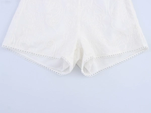 Detailed close-up of white lace embroidery and delicate openwork picot edge on shorts