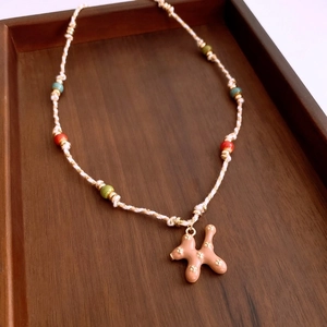 Detailed macro shot of ceramic balloon dog pendant and colorful beads on woven rope necklace