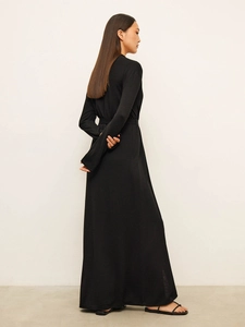 Detail of minimalist black long sleeve maxi dress showing back silhouette and fabric drape