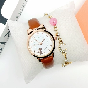 Close-up of cat-ear watch with leather strap and moon pendant bracelet on display pillow