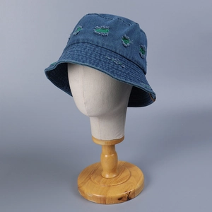 Detailed view of dark blue denim bucket hat featuring green knit distressed hole accents