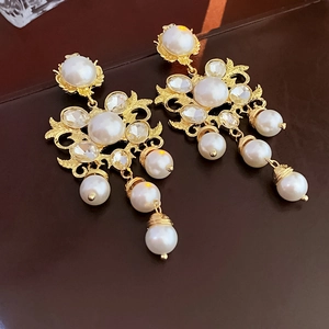 Detailed close-up of vintage gold floral earrings with pearls and crystal tassels