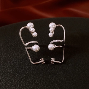 Macro shot of silver pearl ear cuff with zircon accents on dark textured background
