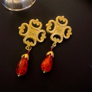 Detailed close-up of vintage gold cloud earrings with translucent red teardrop pendants