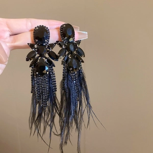 Macro detail of black feather earrings with sparkling rhinestones and long fringe