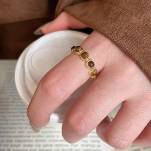 Detail of vintage gold-plated ring with five round tiger eye stones on a finger