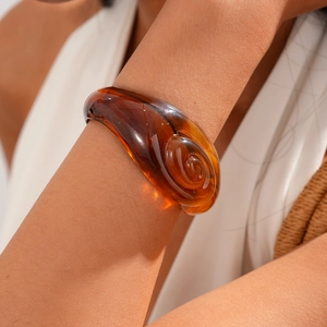 Close-up of amber acrylic spiral bangle showing translucent texture on model wrist