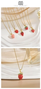 Detail view of red enamel strawberry pendant necklaces with gold chain and green zircons