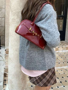 Detail of red patent leather bowling bag featuring golden buckle and classic top handle