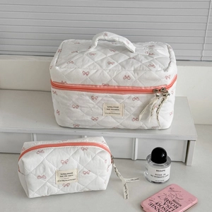 Vue détaillée de la trousse de maquillage matelassée avec nœuds roses et ruban élégant