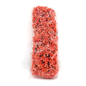 Close-up of artificial red flower stamens with white dots in clear packaging