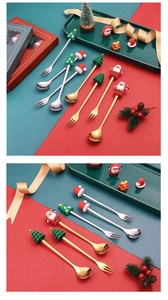 Close-up of golden Christmas spoons and forks with festive Santa and tree handle charms
