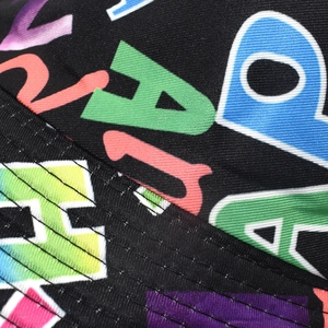 Macro detail showing colorful letter print and stitching on black bucket hat fabric