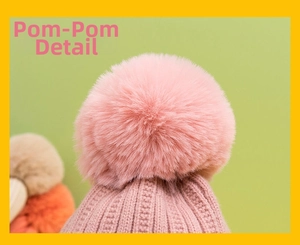 Detailed close-up of a large pink fluffy faux fur pompom on a knit winter hat