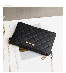 Détail du sac bandoulière matelassé noir avec chaîne dorée et logo en métal brillant