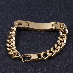 Golden stainless steel Cuban chain bracelet with a curved ID bar on a dark background