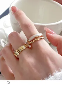 Detail of layered gold rings with geometric texture and white enamel inlay on hand