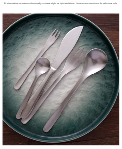 Close-up of matte 304 stainless steel cutlery set on green textured ceramic plate