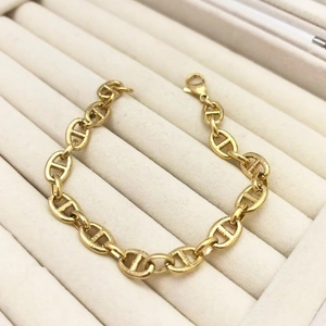 Macro detail of gold-tone pig nose anchor link chain bracelet with lobster clasp